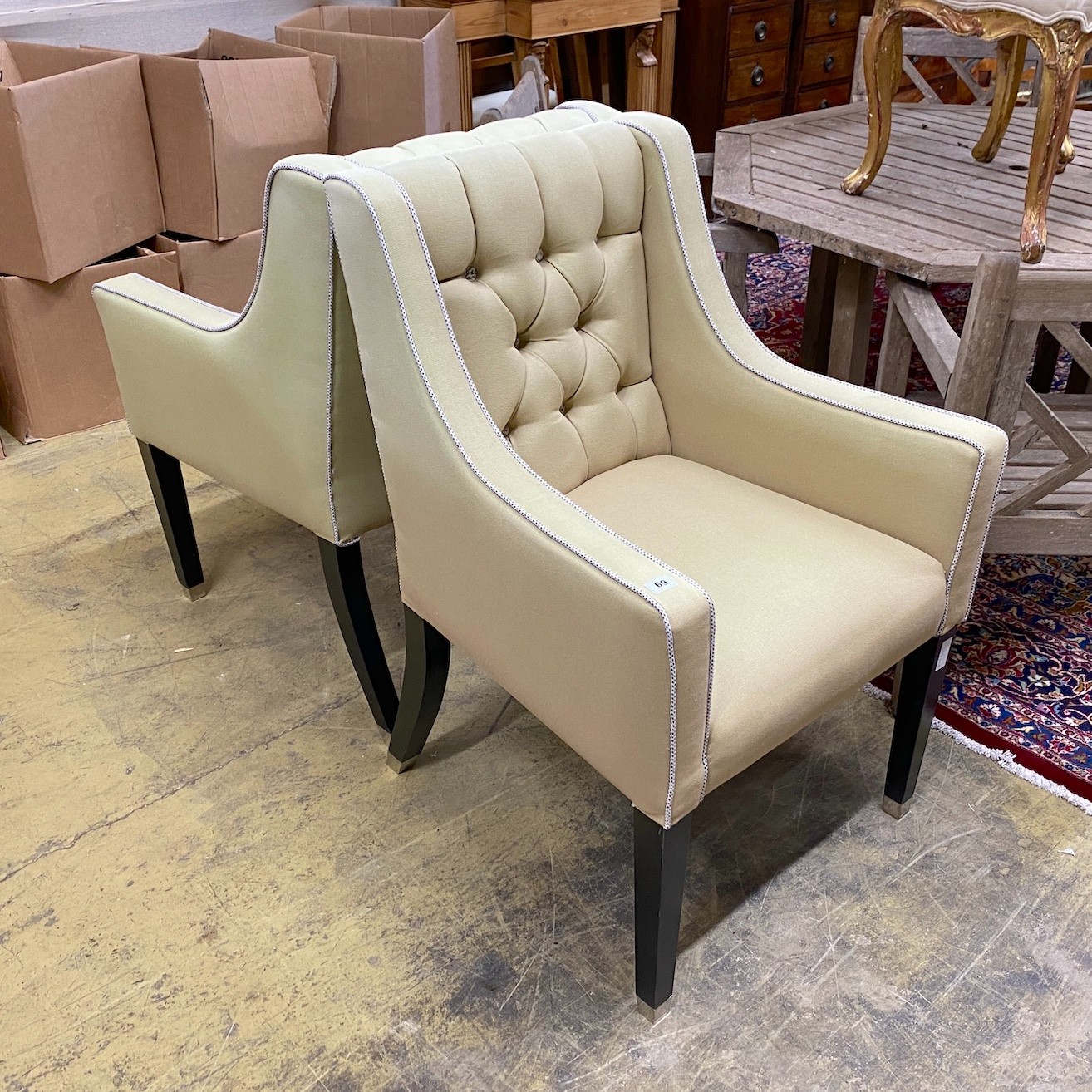 A pair of contemporary armchairs with deep buttoned backs on ebonised underframes, width 64cm, depth 68cm, height 99cm